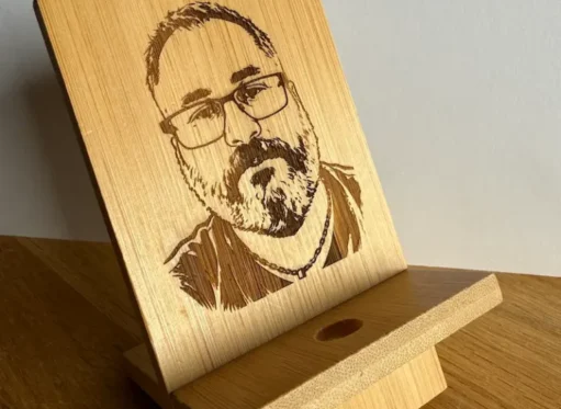 Support de téléphone en bambou gravé au laser avec un portrait d'homme, vue de trois-quarts posée sur une table